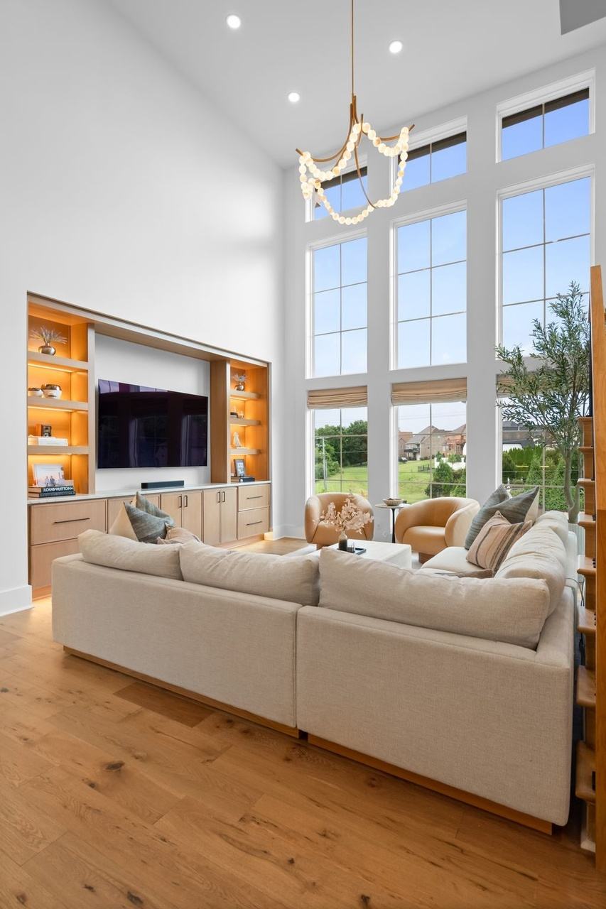 Tall view of the media wall: lit oak shelves either side of the television, the beaded garland chandelier above.