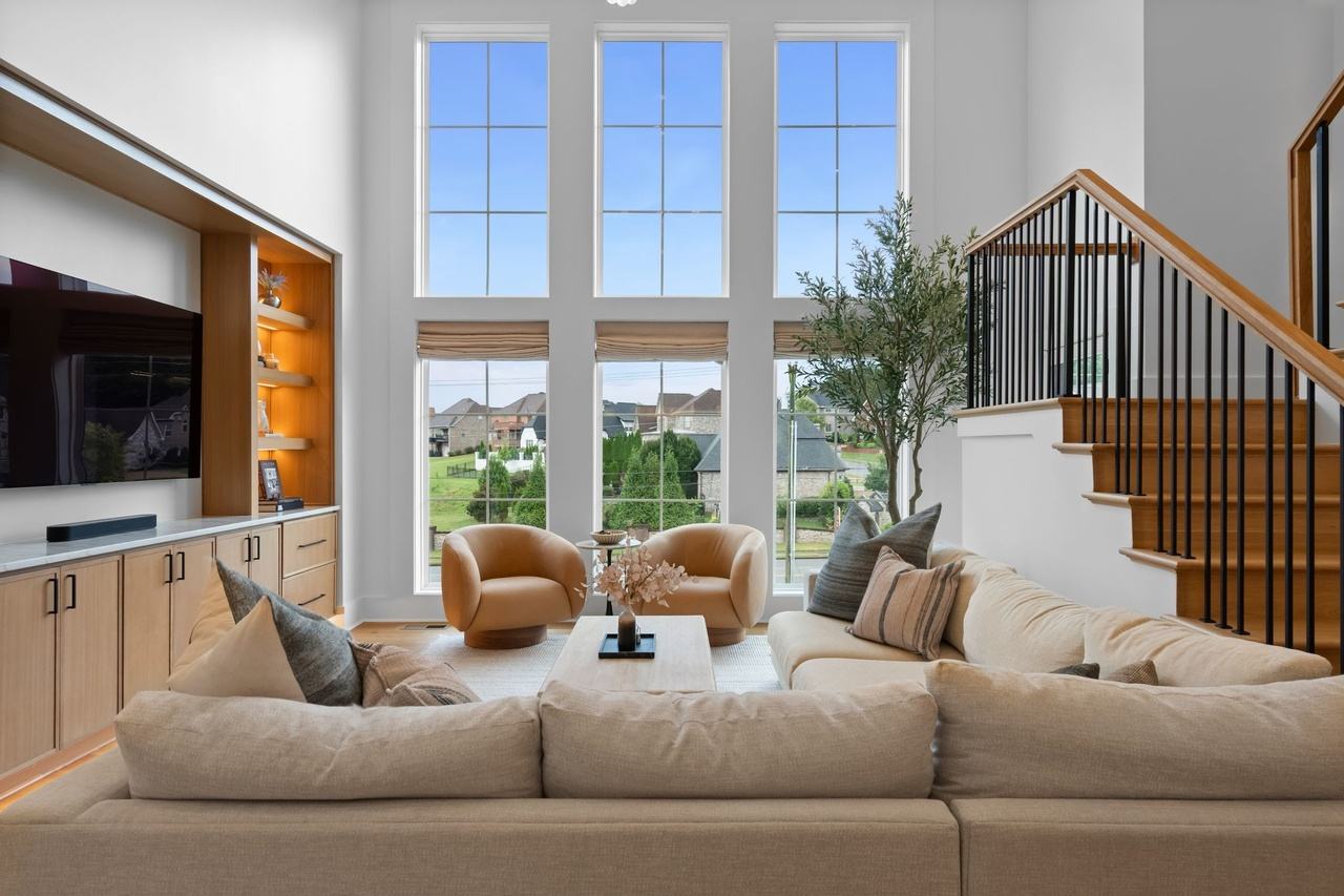From behind the sectional toward the windows, the oak media wall at left and the open stair at right.