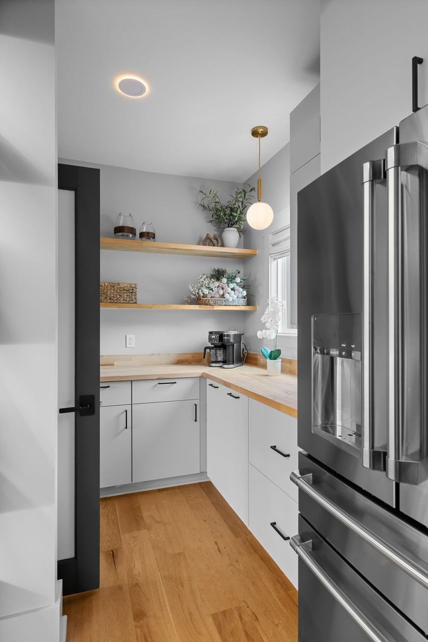 The butler's pantry: a coffee station on a butcher-block counter, open oak shelves and a full-size French-door refrigerator.