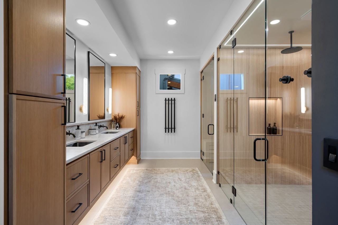 The primary bath along the oak vanity, toward the shower.