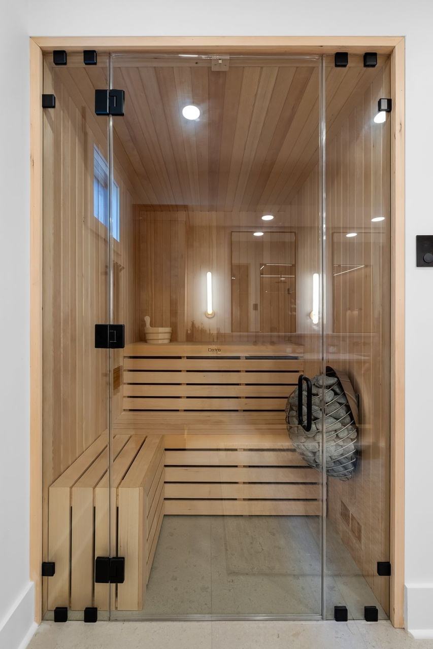 The sauna behind a glass door: cedar walls and tiered benches, a bucket and ladle.