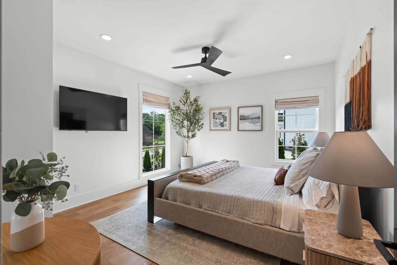 The downstairs guest bedroom from the doorway, an upholstered bed between fluted nightstands.