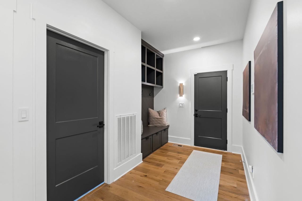 The back hall toward the garage door: dark painted doors, a built-in bench and cubbies, two large copper-toned canvases.