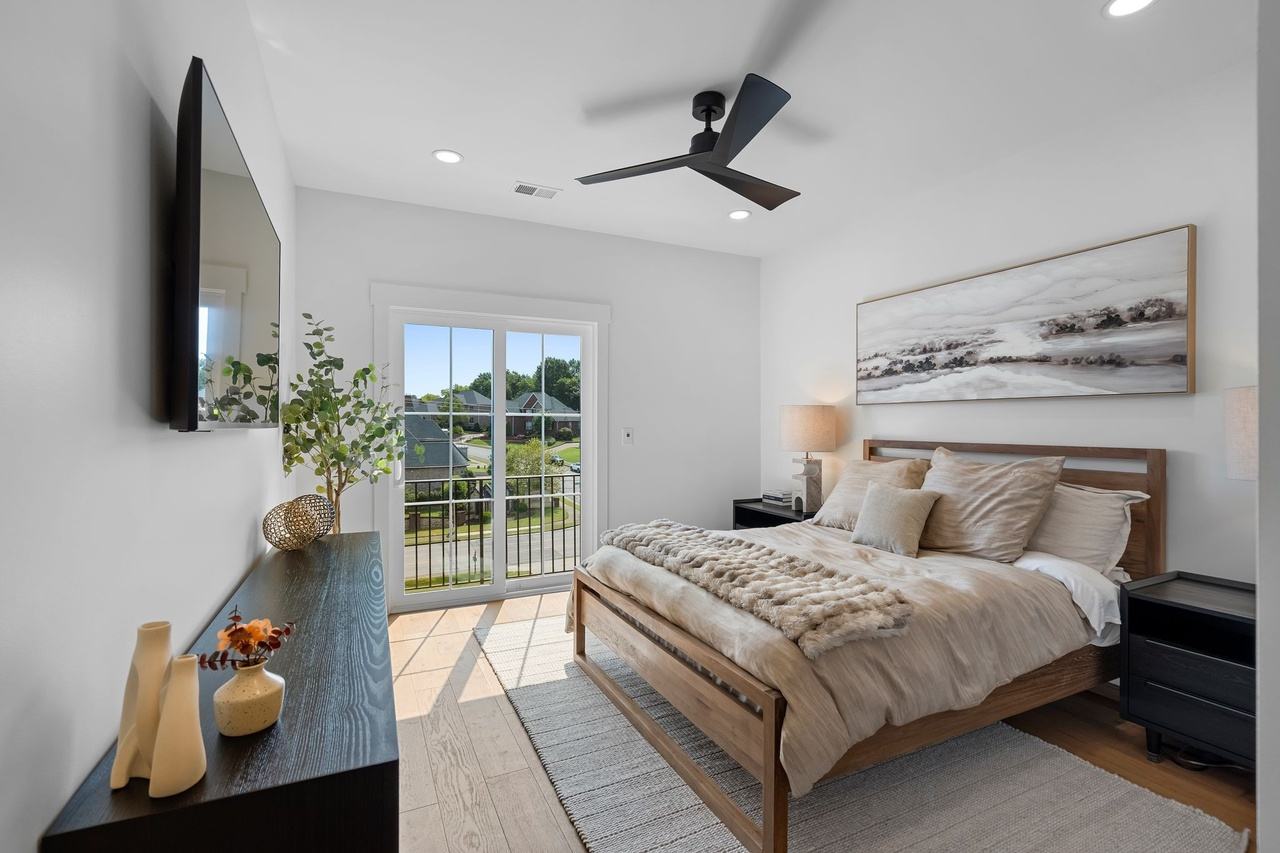 Guest room two: a wood bed under a wide landscape print, a door to the balcony beyond.