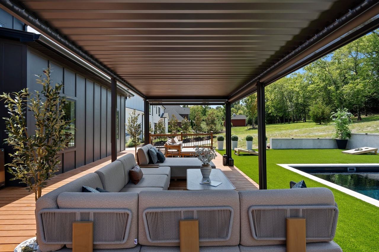 Inside the pergola: a sectional and olive trees in white planters.