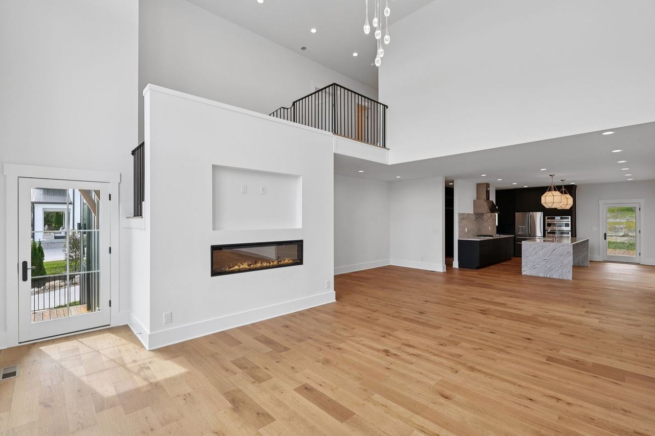 2025 photograph (before): Living Room, toward fireplace wall and kitchen, with linear fireplace, TV niche, loft railing, side door