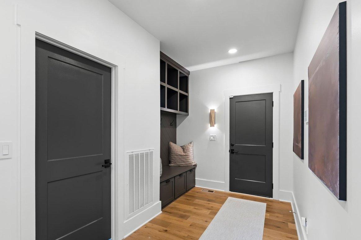 The back hall toward the garage door: dark painted doors, a built-in bench and cubbies, two large copper-toned canvases.