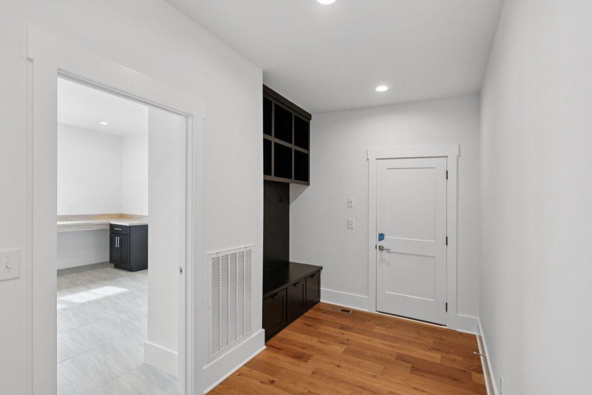 2025 photograph (before): Back Hall, toward end door, with dark mudroom lockers, cubbies, bench, coat hooks