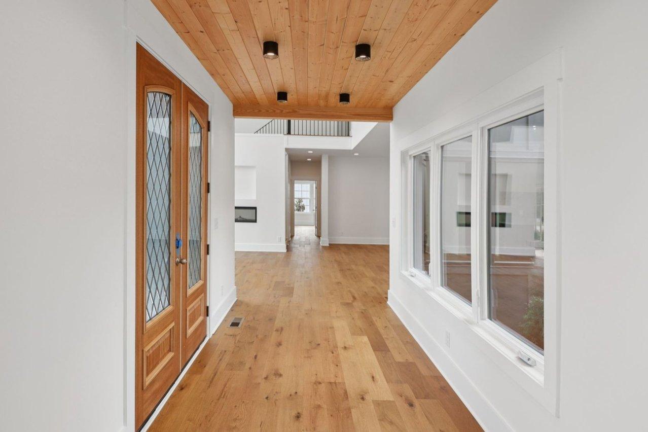 2025 photograph (before): Foyer, with wood plank ceiling, double front doors, hardwood, black can lights