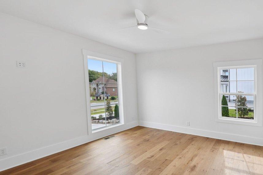 2025 photograph (before): Guest Bedroom, corner toward 2 windows, with tall window, double-hung window, ceiling fan, hardwood