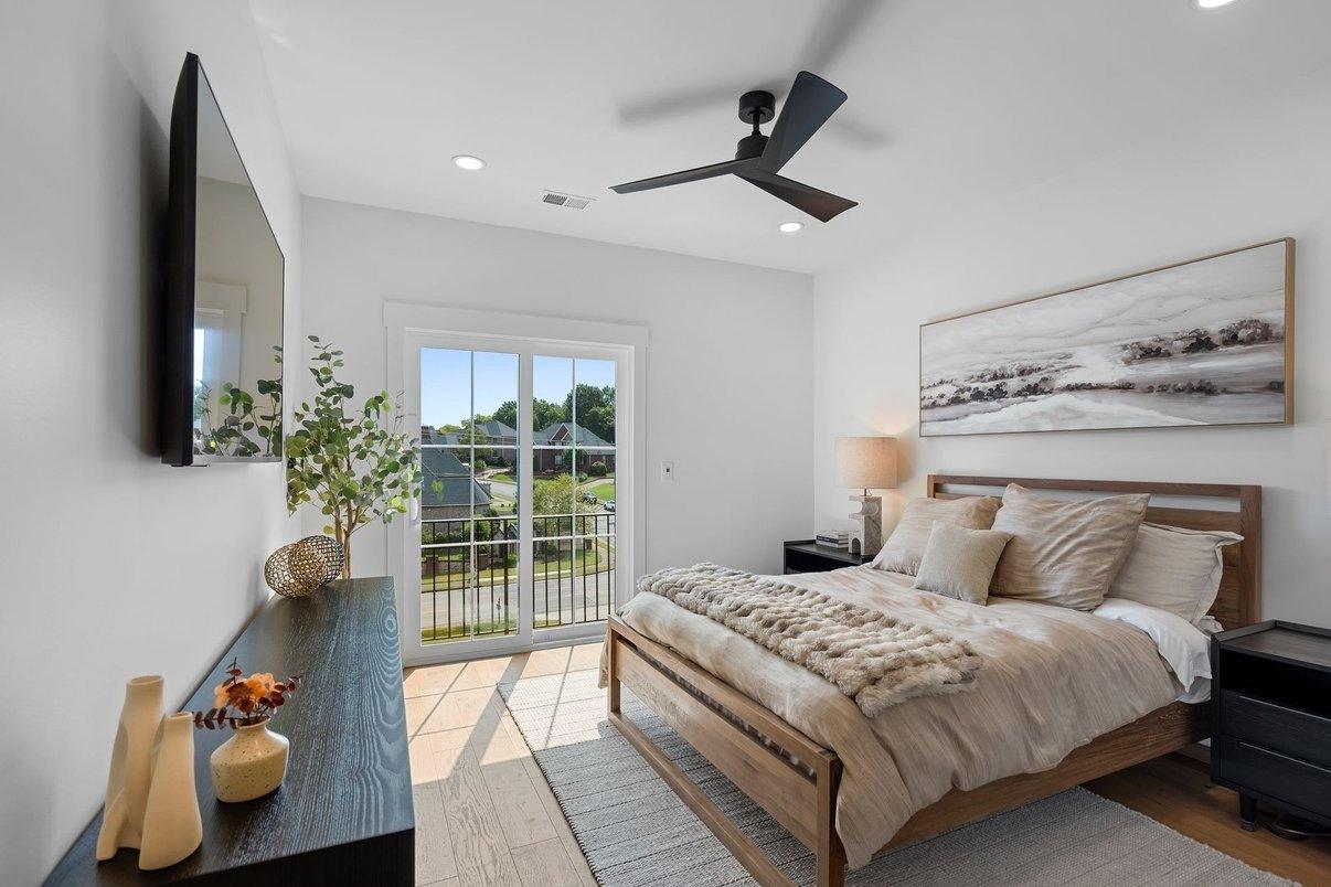 Guest room two: a wood bed under a wide landscape print, a door to the balcony beyond.
