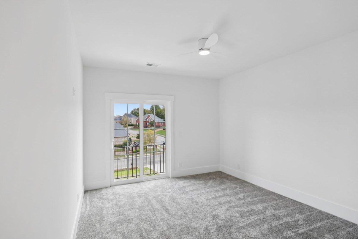 2025 photograph (before): Guest Room 2, toward balcony slider, with balcony sliding door, iron balcony railing, gray carpet, ceiling fan