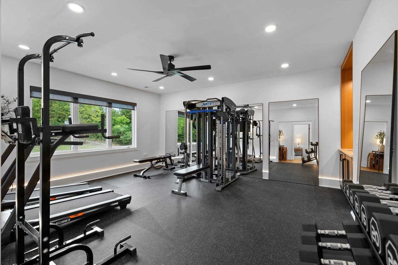 The gym from the doorway: rubber flooring, a cable trainer, two treadmills and full-height mirrors.