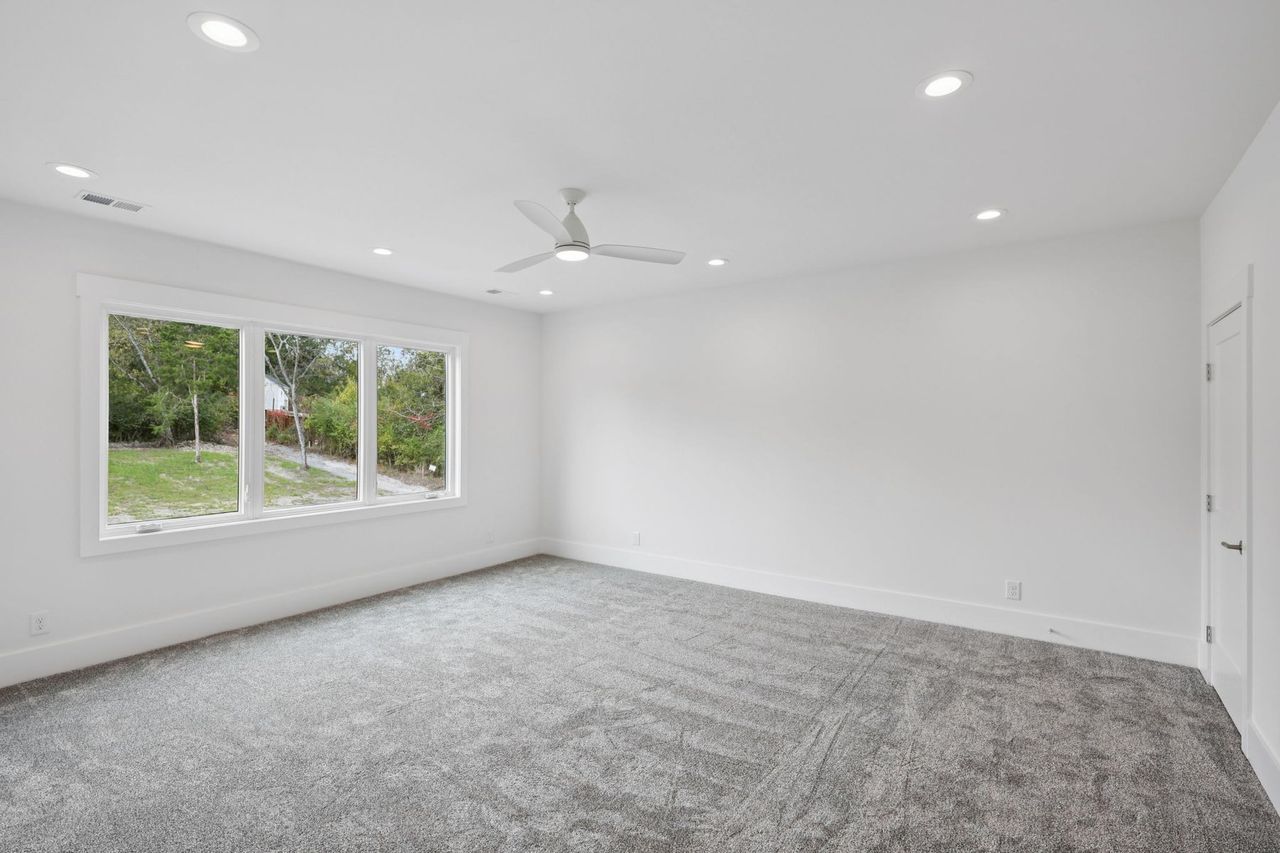 2025 photograph (before): Gym, with triple window, gray carpet, ceiling fan, recessed lights
