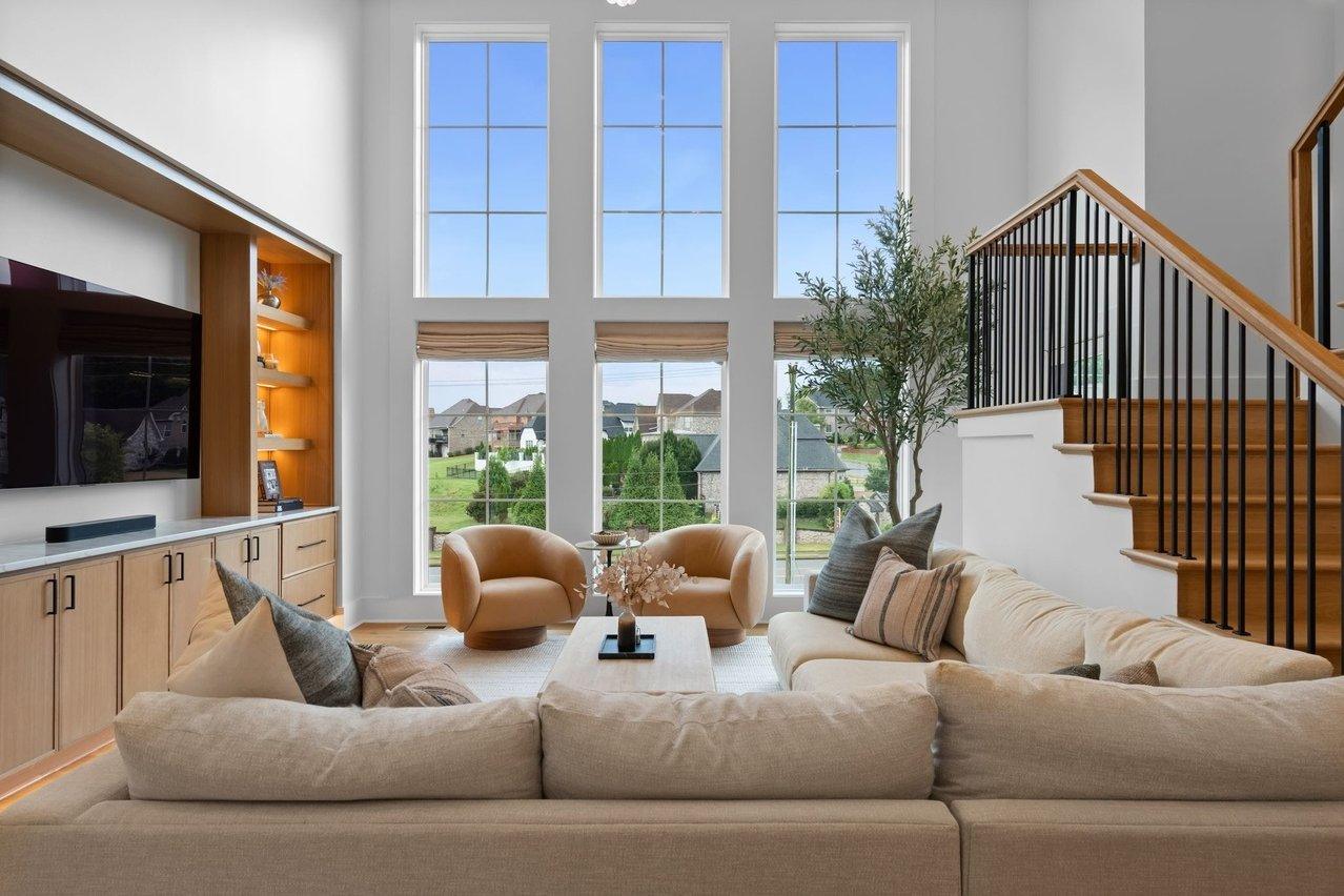 From behind the sectional toward the windows, the oak media wall at left and the open stair at right.