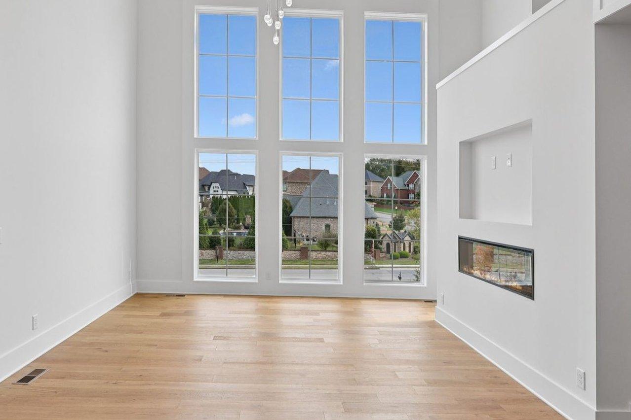 2025 photograph (before): the living room, the wall of windows at the end and a wall with a see-through fireplace beside the stair.
