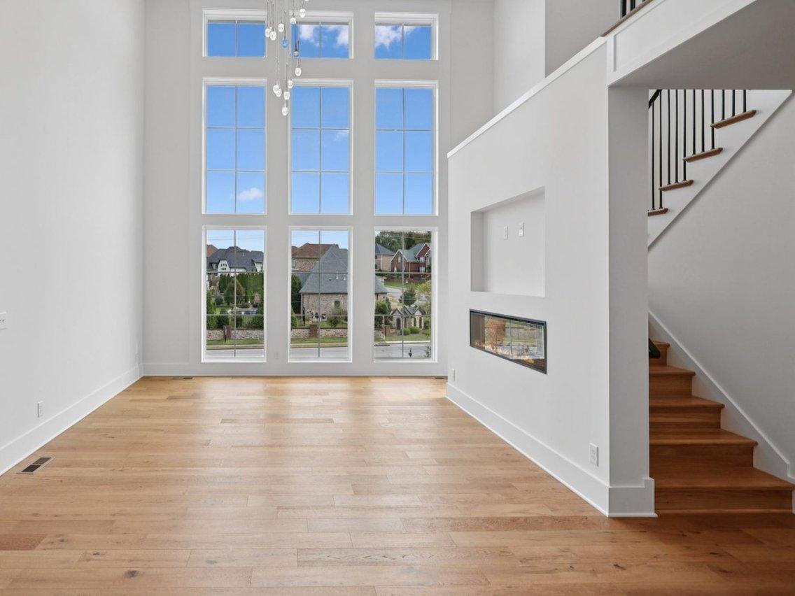 2025 photograph (before): the living room, the wall of windows at the end and a wall with a see-through fireplace beside the stair.