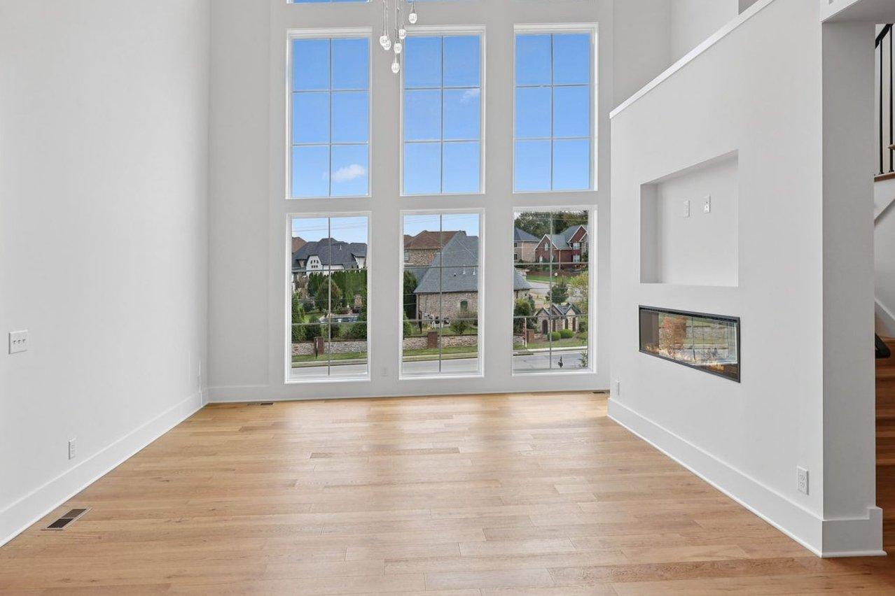 2025 photograph (before): the living room, the wall of windows at the end and a wall with a see-through fireplace beside the stair.