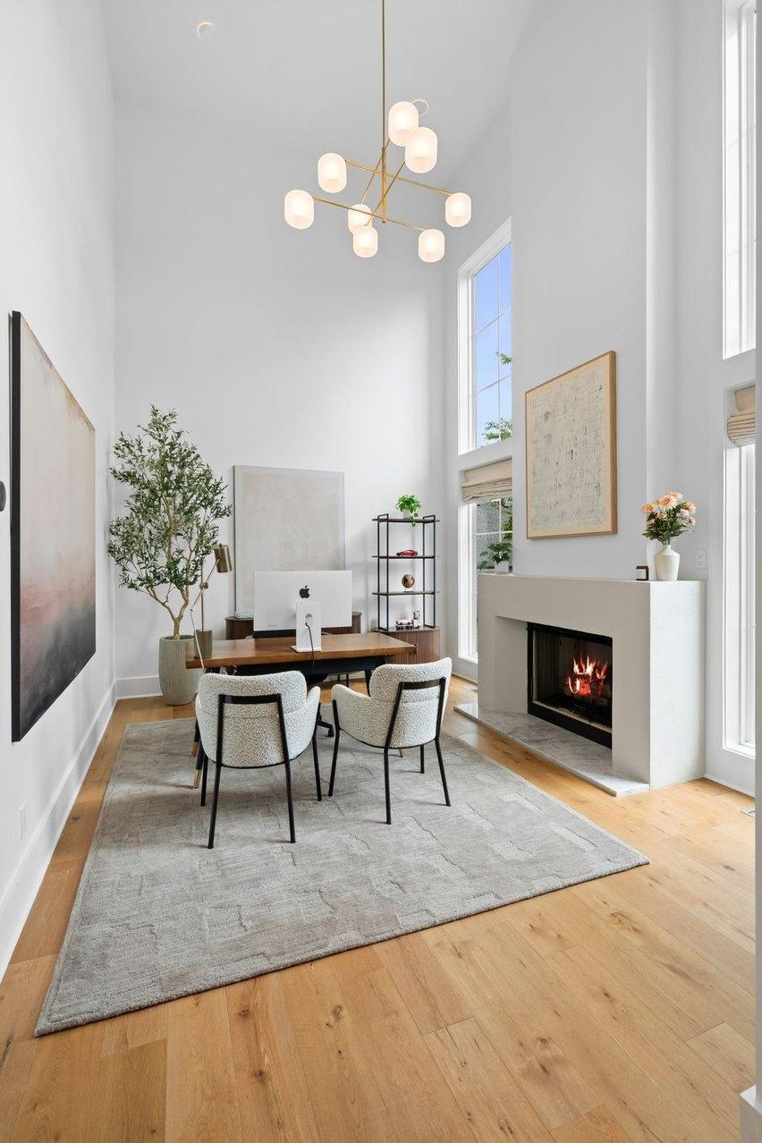 Tall view of the two-story office, a globe chandelier and tall windows on two walls.
