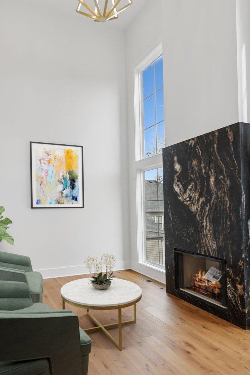 2025 photograph (before): Office, toward fireplace wall, with 2 green swivel chairs, marble fireplace, coffee table, gold pendant