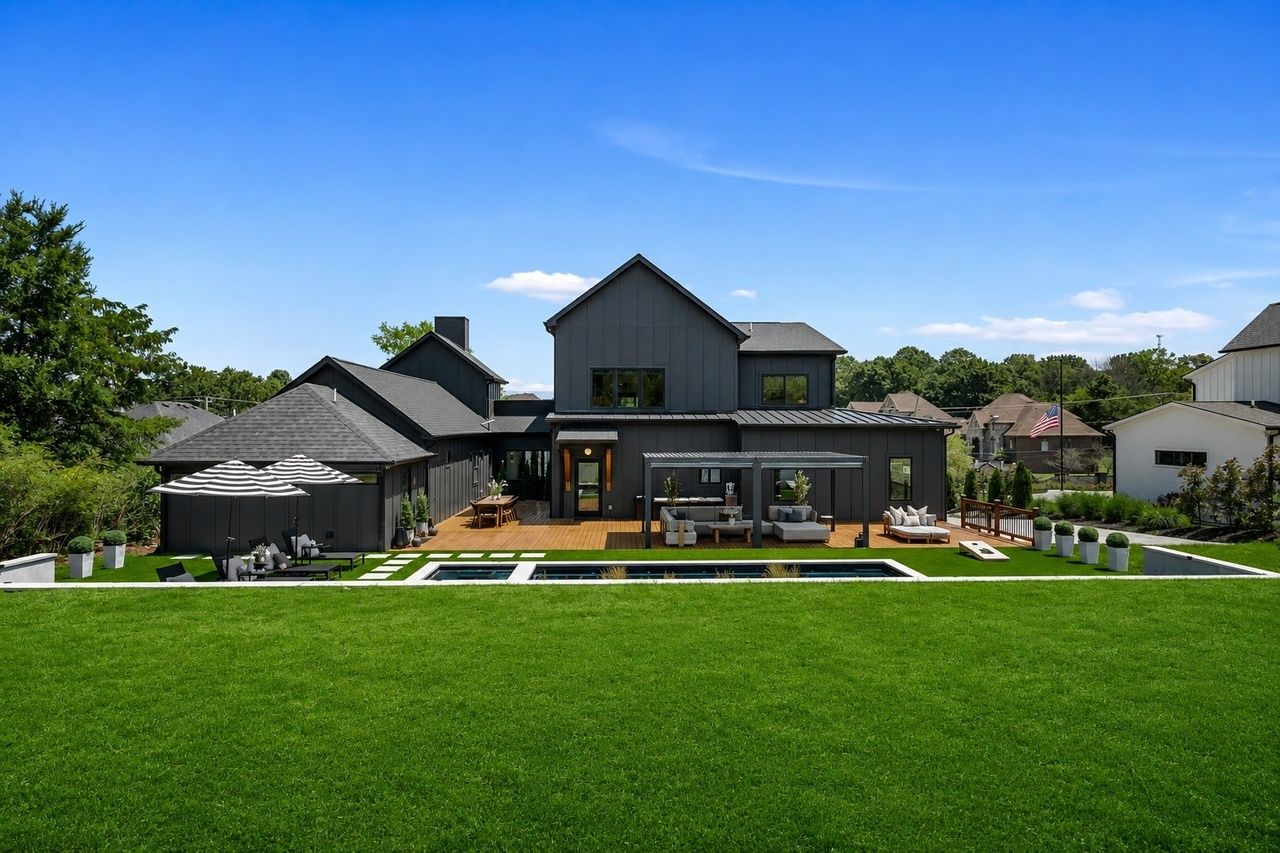 The back of the house straight on from the lawn, the pool and pergola in front of the black board-and-batten wings.