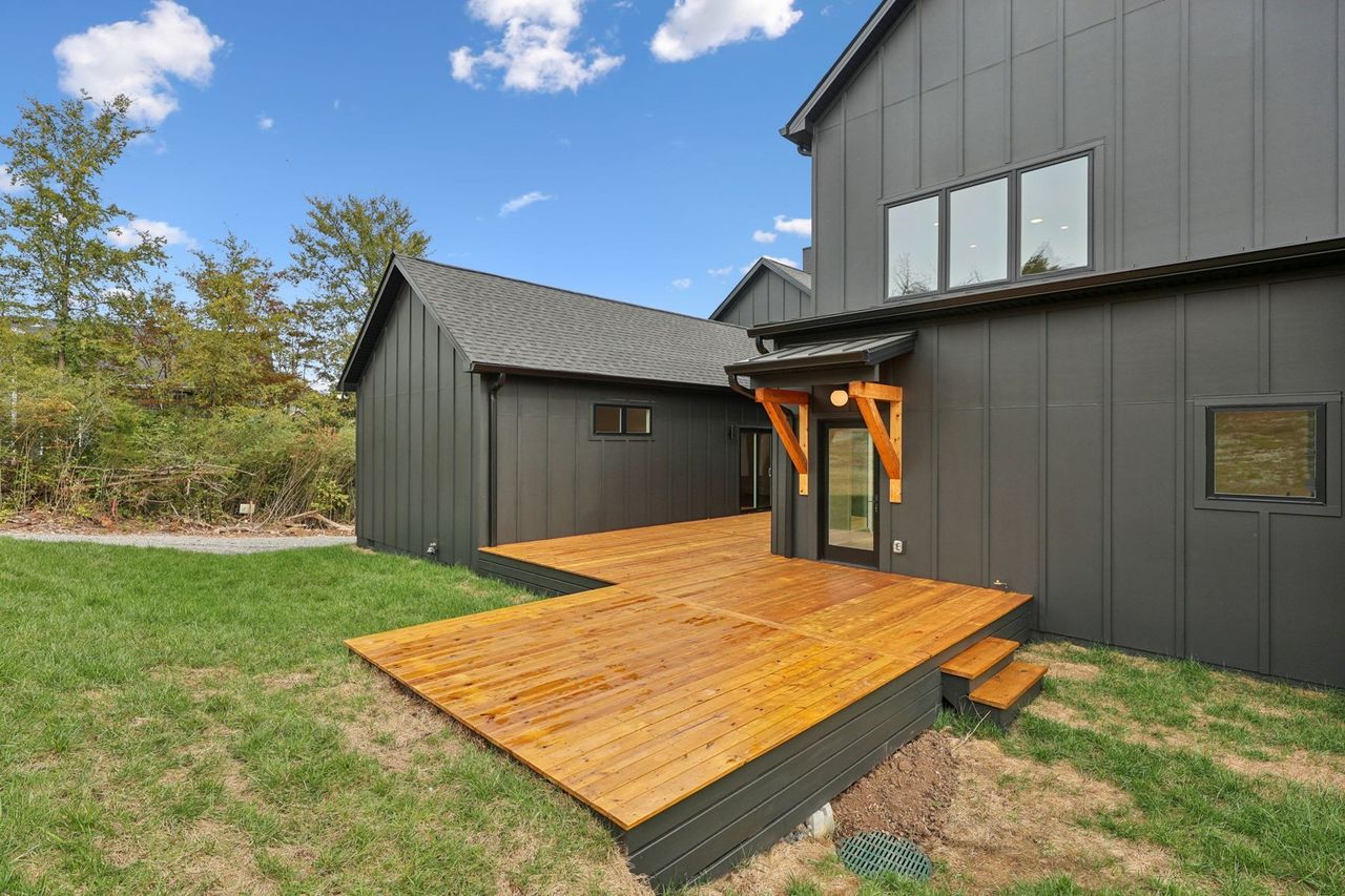 2025 photograph (before): Exterior Rear, from rear lawn at deck steps, with wood deck, deck steps, timber awning, glass back door