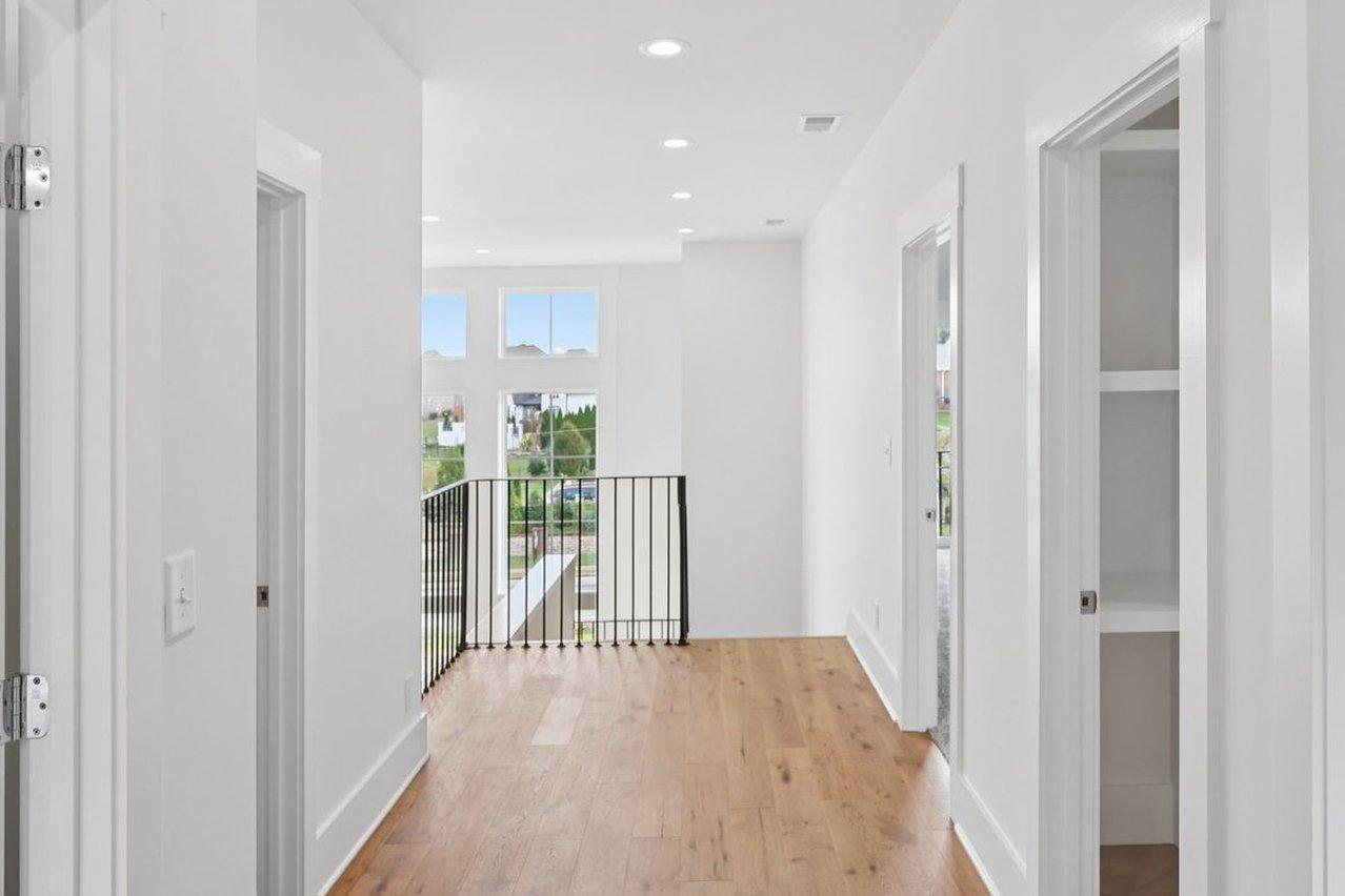 2025 photograph (before): Upstairs Hall, with hardwood, black iron railing, tall front windows, open doors